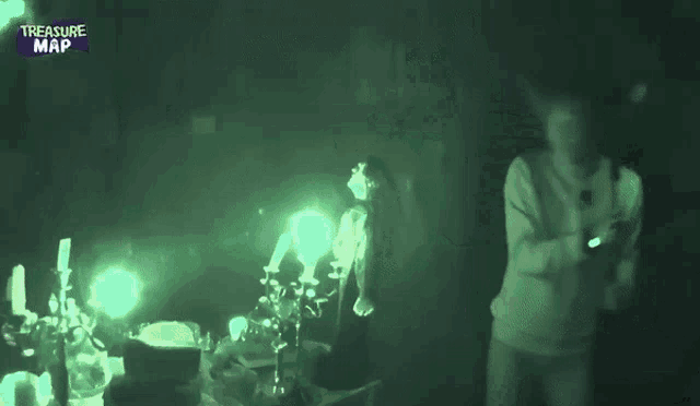 a man and a woman are standing in a dark room with a treasure map logo on the bottom