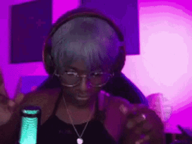a woman wearing headphones and glasses is sitting in a dark room .