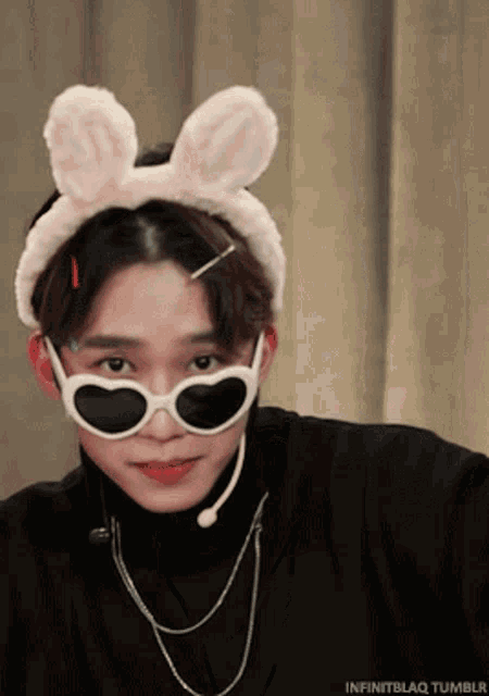 a young man wearing sunglasses and bunny ears looks at the camera