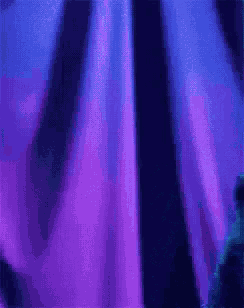 a close up of a purple and blue curtain in the dark