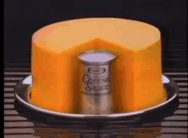 a can of cheese sauce is sitting on a plate with a piece of cheese on top .