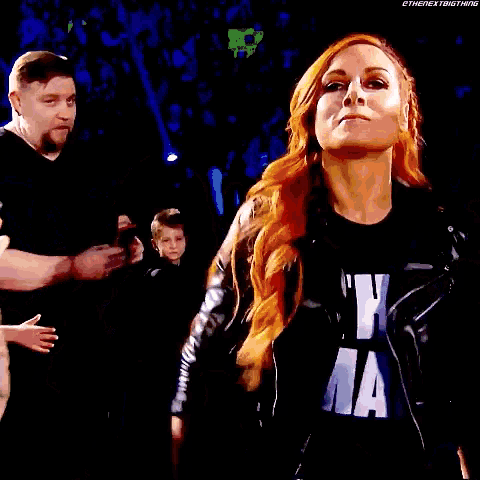 a woman stands in front of a wrestlemania logo