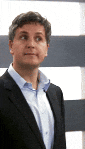a man wearing a suit and a blue shirt looks to his left
