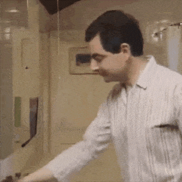 a man in a striped shirt is standing in front of a glass door .