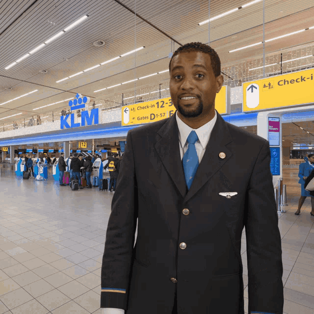 a man in a suit and tie stands in front of a klm sign