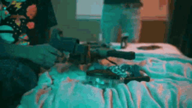 a person is sitting on a bed with a gun and a lighter .