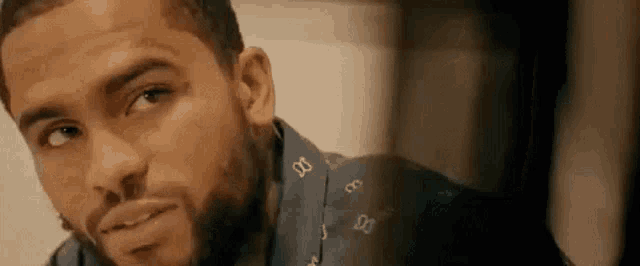 a close up of a man with a beard wearing a blue shirt and a scarf .