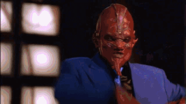 a man with a red mask on his face is wearing a blue suit