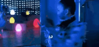 a person is taking a picture of another person in a dark room with a lot of lights .