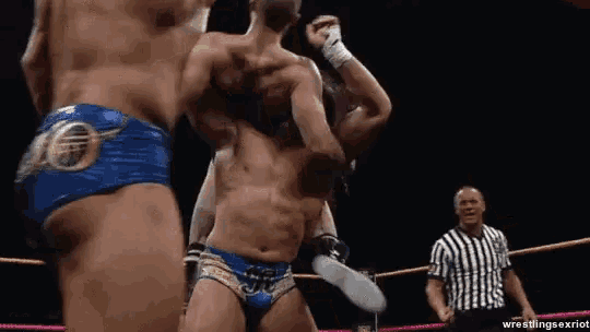 two men are wrestling in a wrestling ring with a referee watching .