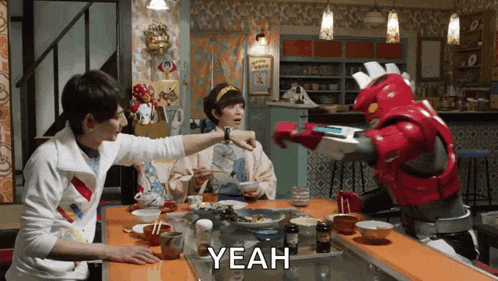 a group of people are sitting at a table with a robot that says yeah on it