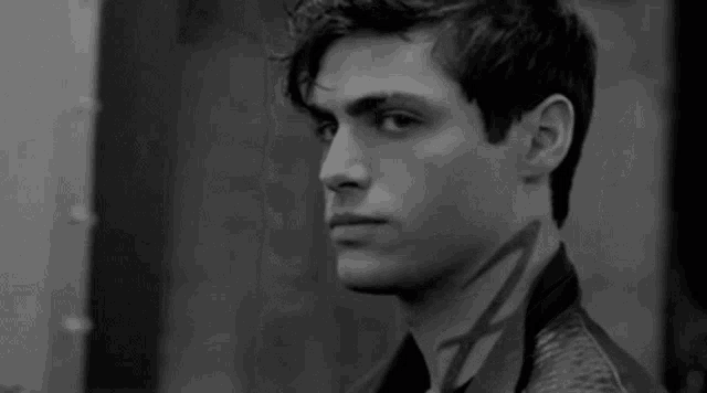 a black and white photo of a young man looking at the camera .