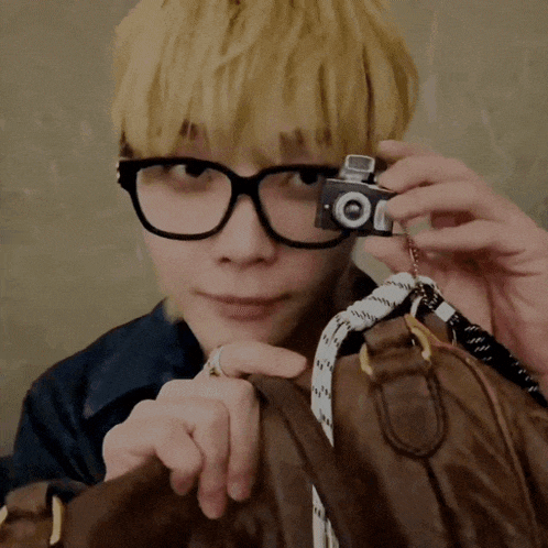 a man wearing glasses is holding a small camera that says ' oi ' on it