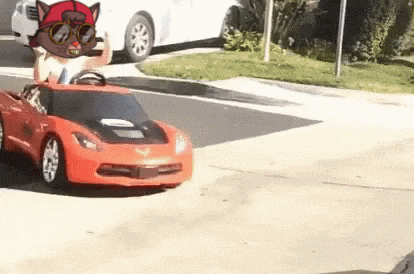 a person is driving a red toy car on the street .