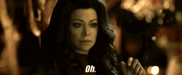 a woman in a dark room says oh in front of a blurry background