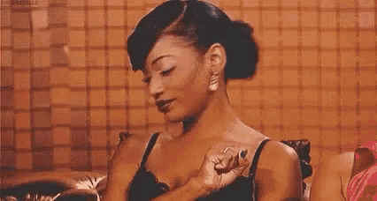 a woman in a black bra is sitting on a couch and holding her chest .
