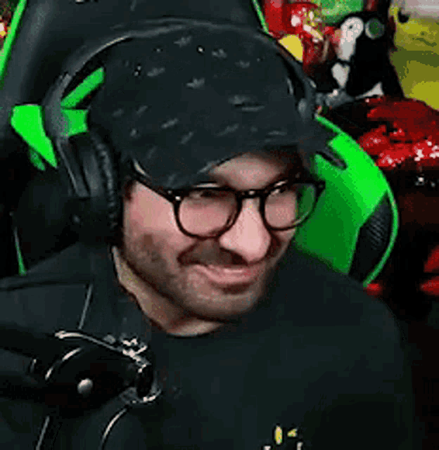 a man wearing glasses and headphones is sitting in a green chair and making a funny face .