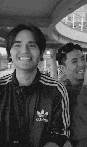 a black and white photo of a man wearing a black adidas jacket