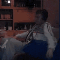 a man wearing headphones sits on a couch in a living room