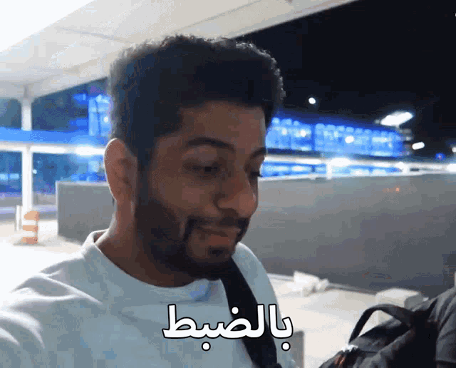a man with a beard is smiling with arabic writing behind him