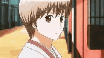 a young boy in a kimono is standing in front of a building looking at the camera .
