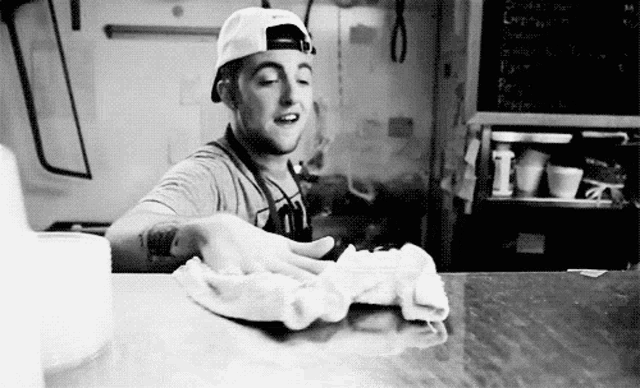 a man is cleaning a counter with a towel in a kitchen .