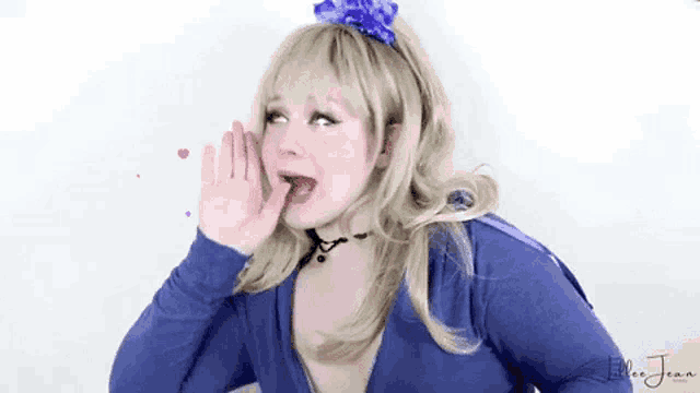 a woman with blonde hair and a blue shirt is whispering into someone 's ear