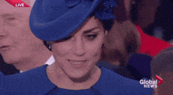 a woman wearing a blue hat and a blue dress is smiling while sitting in a crowd .