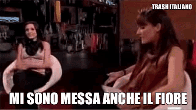 two women are sitting next to each other and the words mi sono messa anche il fiore are on the screen