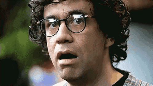a man with curly hair and glasses is making a funny face .