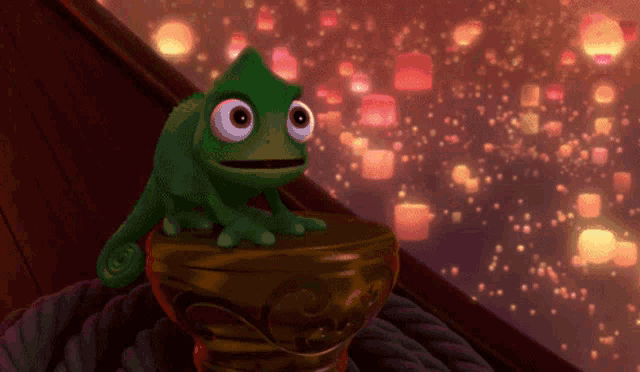 a green cartoon character with big eyes is sitting on a gold object