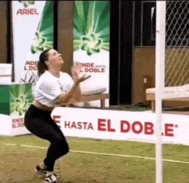 a woman is squatting down in front of a sign that says hasta el dobe