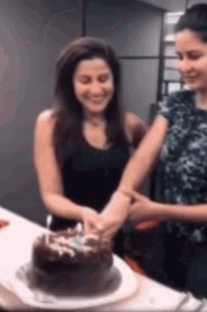 two women are cutting a cake with a blue ribbon that says ' i love you ' on it