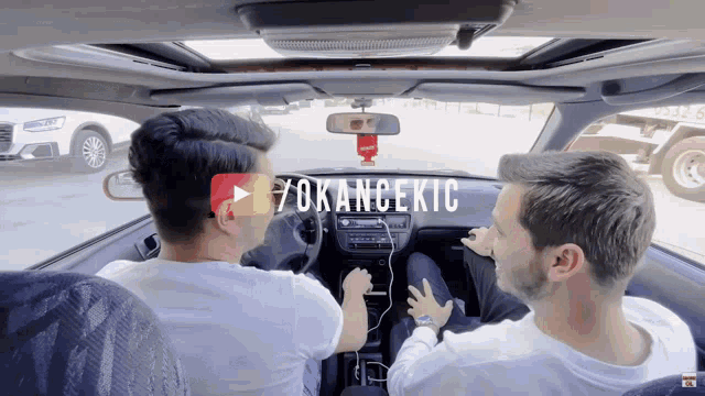 two men are sitting in a car with a play button above them that says " yokancekic "