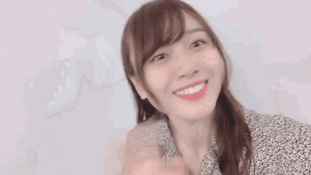 a woman in a floral shirt is making a funny face while looking at the camera .