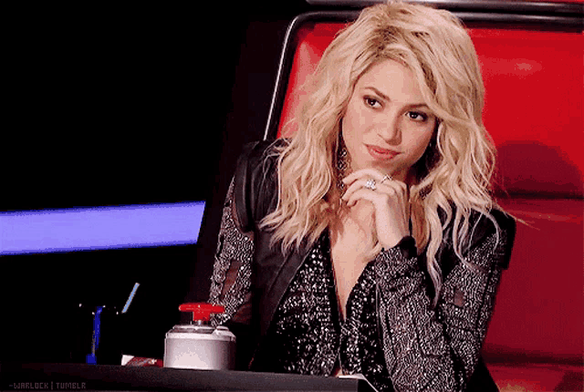 a woman with blonde hair is sitting in a chair with a red button on it