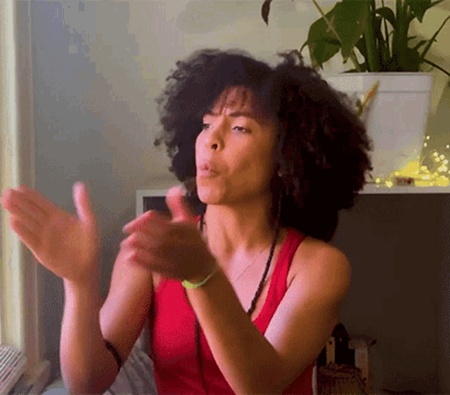 a woman wearing a red tank top is clapping her hands