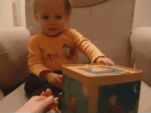 a toddler wearing a shirt that says ' a ' on it is playing with a toy box