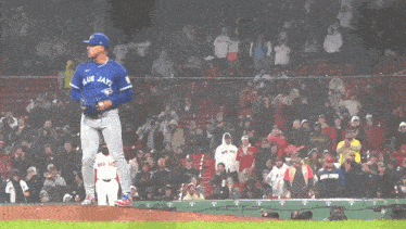 a pitcher for the blue jays stands on the mound in front of a crowd