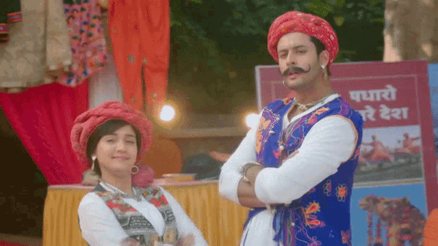 a man with a mustache is standing next to a woman in front of a sign that says ' maharas ' on it