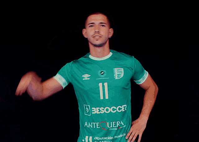 a man wearing a green besoccer jersey holds up his fist