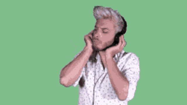 a man wearing headphones and a white shirt is listening to music on a green background .