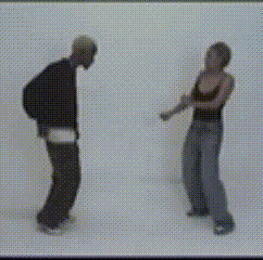 a man and a woman are dancing in front of a white wall