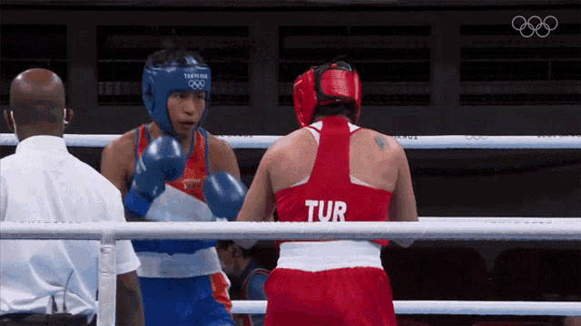 two female boxers in a ring one of whom is wearing a tur shirt