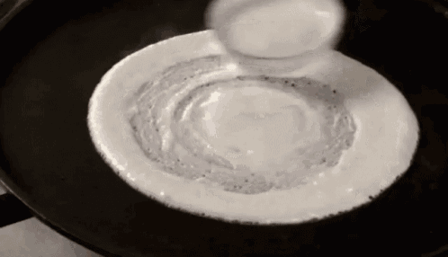 a black and white photo of a pancake being cooked on a pan