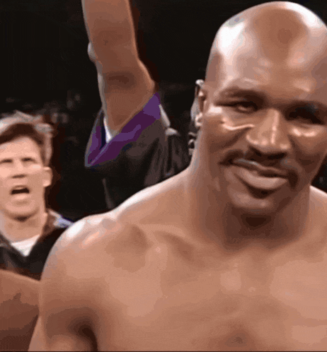a bald man with a mustache is smiling while a referee looks on