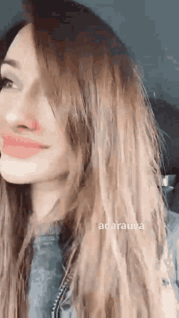 a close up of a woman 's face with long hair and a pink lip .