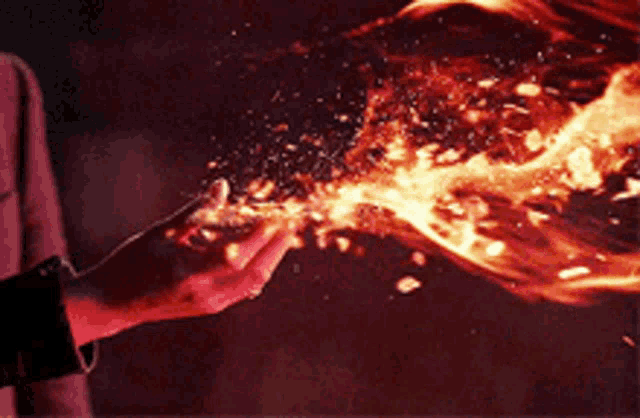 a person is holding a flame in their hands in a dark room