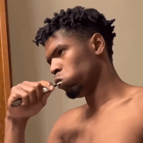 a shirtless man brushing his teeth with a toothbrush