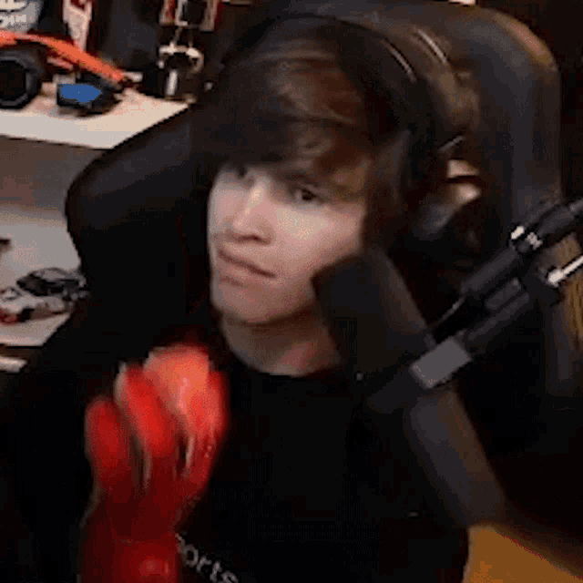a young man is sitting in a chair with a microphone and holding a lobster .